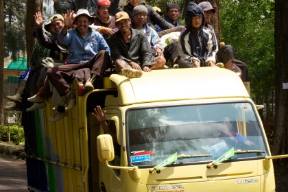 Photo of a group of people riding on the back of a yellow truck, Indonesia, February 2013, Reinder Nijhoff