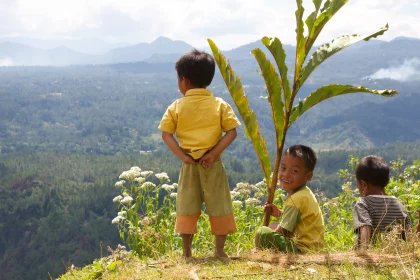 Photo of three children sitting on a hill with a tree, Indonesia, February 2013, Reinder Nijhoff