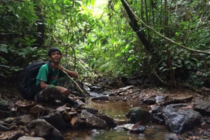 Photo of a man kneeling down in the middle of a stream, Indonesia, August 2014, Reinder Nijhoff
