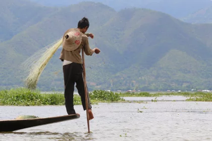 Photo of a man standing on a boat in the water, Myanmar, India, Nepal, June 2015, Reinder Nijhoff