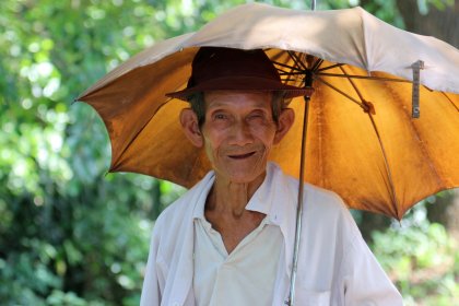 Photo of a man with a hat holding an umbrella, Myanmar, India, Nepal, June 2015, Reinder Nijhoff