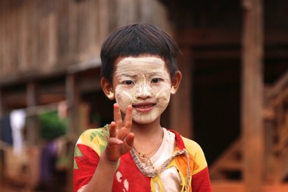 Photo of a young boy with a face mask on giving the peace sign, Myanmar, India, Nepal, June 2015, Reinder Nijhoff