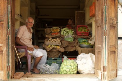 Photo of a man sitting in the back of a truck filled with produce, Myanmar, India, Nepal, June 2015, Reinder Nijhoff