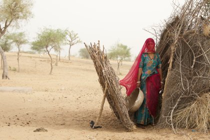 Photo of a woman standing next to a pile of dry grass, Myanmar, India, Nepal, June 2015, Reinder Nijhoff