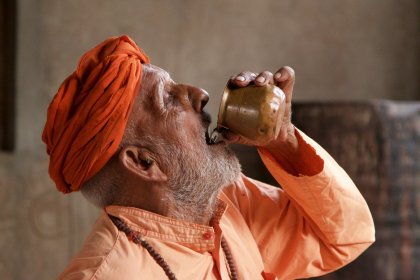 Photo of a man in an orange turban drinking from a cup, Myanmar, India, Nepal, June 2015, Reinder Nijhoff