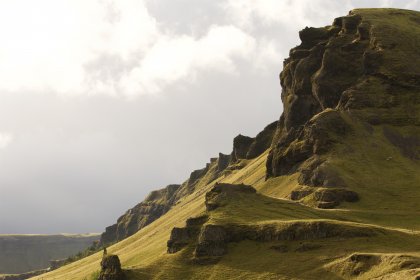 Photo of a person walking up a grassy hill with a mountain in the background, Iceland, September 2015, Reinder Nijhoff