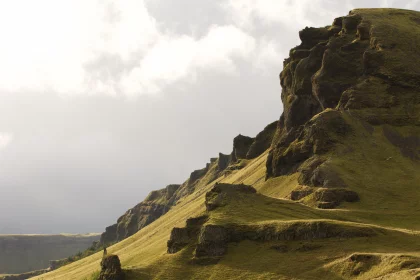 Photo of a person walking up a grassy hill with a mountain in the background, Iceland, September 2015, Reinder Nijhoff