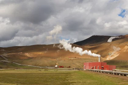 Photo of a red train traveling down train tracks next to a mountain, Iceland, June 2016, Reinder Nijhoff