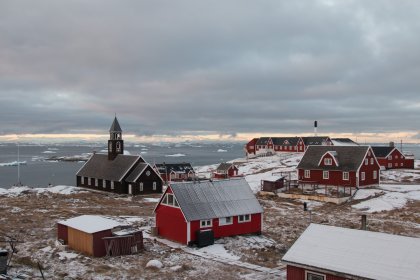 Photo of a group of red buildings sitting on top of a snow covered field, Greenland, October 2017, Reinder Nijhoff