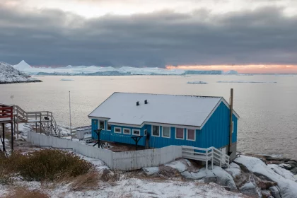 Photo of a small blue house sitting on top of a snow covered hill, Greenland, October 2017, Reinder Nijhoff