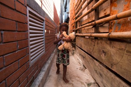 Photo of a little girl holding a teddy bear next to a wooden fence, Santa Cruz del Islote, Colombia, December 2017, Reinder Nijhoff