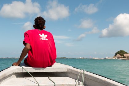 Photo of a man in a red shirt is sitting on a boat, Santa Cruz del Islote, Colombia, December 2017, Reinder Nijhoff