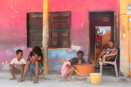 Photo of a group of children sitting outside of a pink building, Santa Cruz del Islote, Colombia, December 2017, Reinder Nijhoff