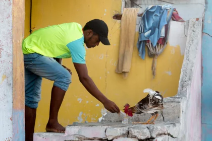 Photo of a man feeding a bird with a knife, Santa Cruz del Islote, Colombia, December 2017, Reinder Nijhoff