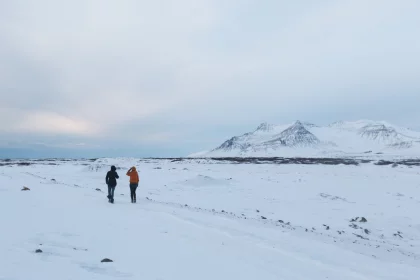 Photo of a couple of people walking across a snow covered field, Winter Iceland, January 2018, Reinder Nijhoff