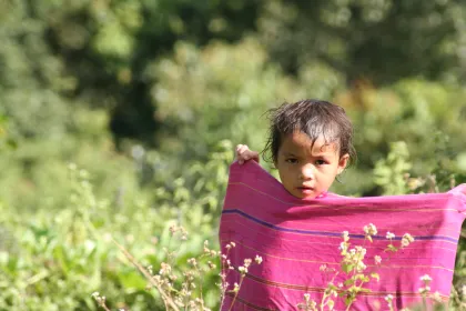 Photo of a young boy holding a pink towel in a field, Thailand, Laos, Cambodja & Vietnam, November 2005, Reinder Nijhoff