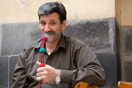 Photo of a man smoking a pipe on a street corner, Jordan, Syria, Lebanon, May 2009, Reinder Nijhoff