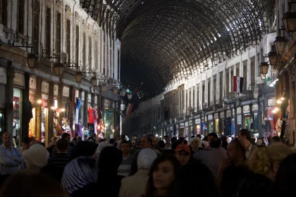 Photo of a crowd of people walking down a street next to tall buildings, Jordan, Syria, Lebanon, May 2009, Reinder Nijhoff