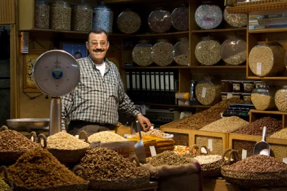 Photo of a man standing in a store filled with lots of food, Jordan, Syria, Lebanon, May 2009, Reinder Nijhoff